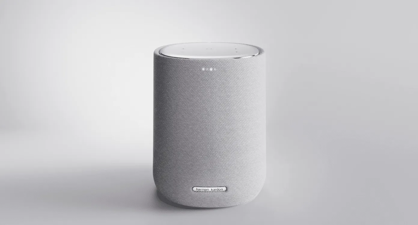 A Harman Kardon speaker wrapped in grey fabric, on a light grey background